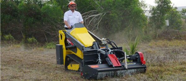 Man wearing safety gear riding on machine with SWMA skid attachment